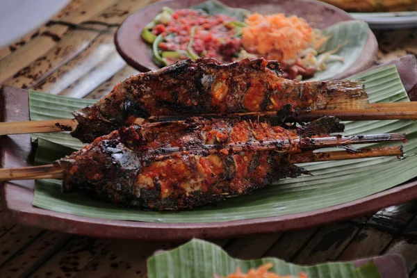 Geleneksel Endonezya Izgara Balığı Muz Yaprağı Servisi Sambal ve Salata eşliğinde Doğal Işığı Destekleyen Yerel Mutfak