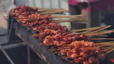 Izgara tavuk şişleri Endonezya mutfağı için dumanlı kömür ocağında hazırlanıyor.