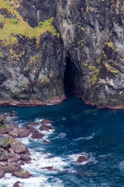 Karanlık Deniz Mağara Girişli Engebeli Kıyı Uçurumu, Derin Mavi Okyanus Suyu ve Kayalıklara Çarpan Dalgalar.