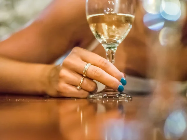 Bir kadeh beyaz şarap tutan kadının el