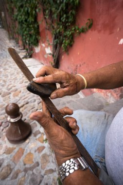 hands of a worker sharpening a rusty machete in Mexico clipart