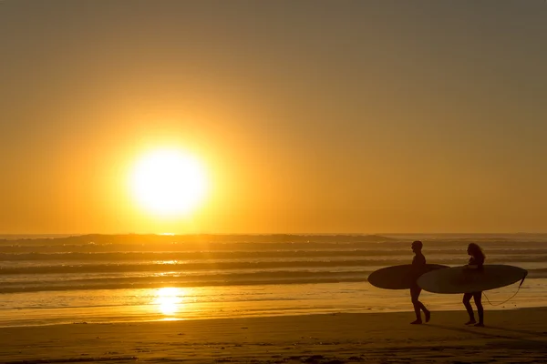 Günbatımında Sahilde yürüyüş surfers — Stok fotoğraf