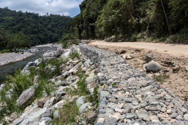 metal mesh and rock retaining wall along road in Honduras  clipart