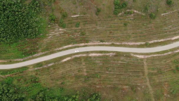 Dron záběry bílého auta projíždějícího krásnou zelenou krajinou v letní den. Letecký pohled na úžasnou nedotčenou přírodu na venkově. — Stock video