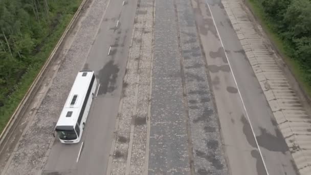 Travel white bus driving on autobahn through the woods White bus fast speed moving on two sided highway. Aerial drone wide shot at summer — Stock Video