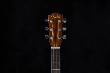 Çamurluk akustik gitar başlığı, krom ayar mandalları ve izole edilmiş siyah arka planda fretboard.