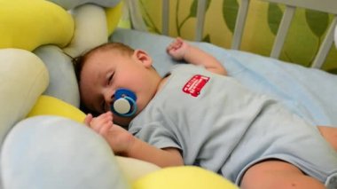 Sevimli yeni doğmuş bebek çocuk bebeğiyle kötü bir şekilde uyuyor ve emzik emiyor.