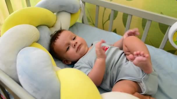 Lindo recién nacido niño se encuentra en su cuna y juega con sus pies — Vídeos de Stock