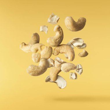 Havaya düşen taze kaju fıstıkları sarı aydınlatıcı arka planda izole edilmiş. Yiyecek uçurma konsepti. Yüksek çözünürlük.