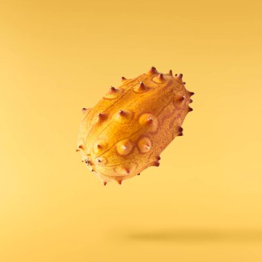 Havaya düşen taze kiwano sarı arka planda izole edilmiş. Sıfır yerçekimi ya da havada kalma. Yüksek kaliteli çözünürlük resmi