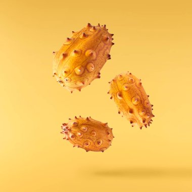 Havaya düşen taze kiwano sarı arka planda izole edilmiş. Sıfır yerçekimi ya da havada kalma. Yüksek kaliteli çözünürlük resmi