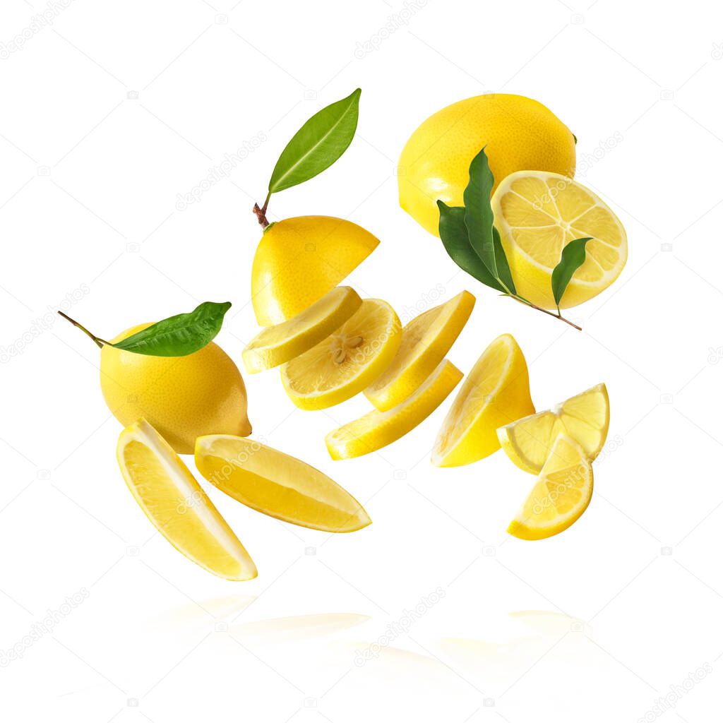 Fresh raw whole and cut lemons with green leaves falling in the air isolated on white background. Food levitation or zero gravity conception. High resolution image