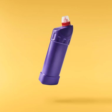 Ev temizlik ürünü. Sarı arka planda izole edilmiş plastik bir şişe havaya düşüyor. Markan için ürün modeli.