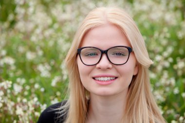 Çiçeklerle çevrili gözlüklü sarışın kız