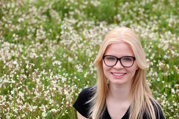 Chica rubia con gafas rodeada de flores — Foto de Stock