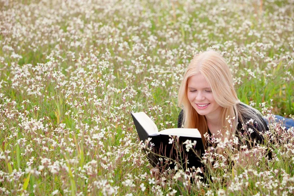 Mujer joven leyendo un libro en el prado — Foto de Stock