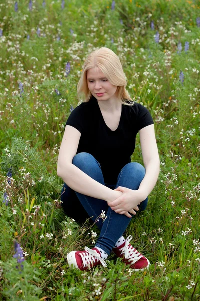 Mooi blond meisje omringd door bloemen — Stockfoto