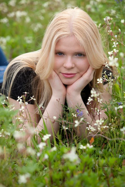 Mooi blond meisje omringd door bloemen — Stockfoto