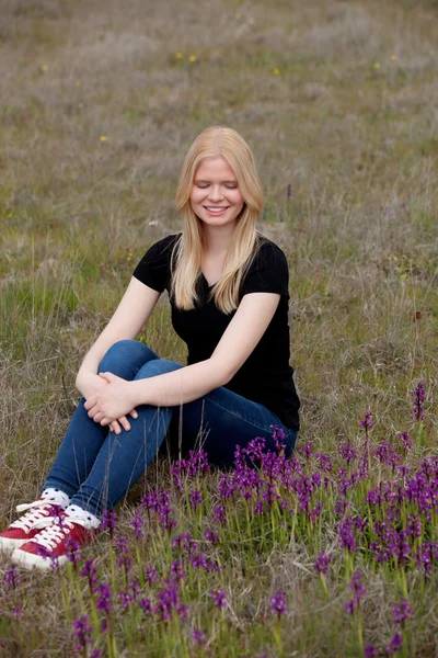 Hermosa chica rubia rodeada de flores — Foto de Stock