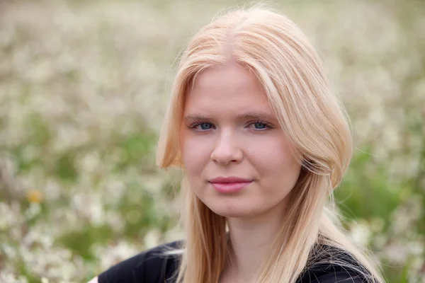 Chica rubia feliz rodeada de flores — Foto de Stock