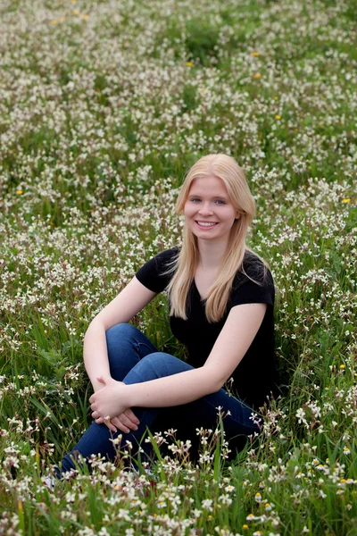 Chica rubia feliz rodeada de flores — Foto de Stock