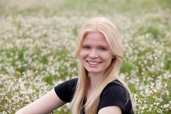 Happy blonde girl surrounded by flowers — Stock Photo, Image