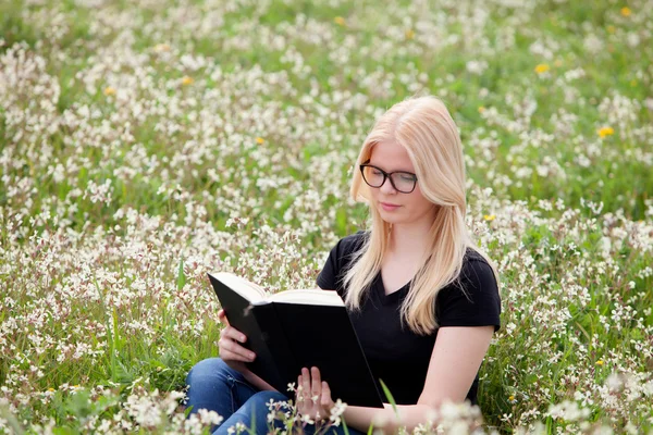 Mujer joven leyendo un libro en el prado — Foto de Stock