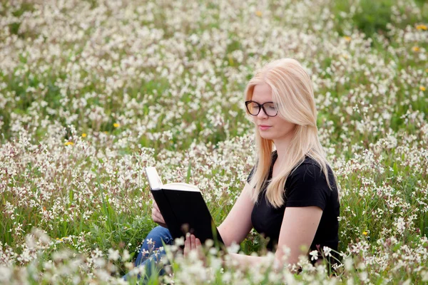 Молода жінка читає книгу на лузі — стокове фото
