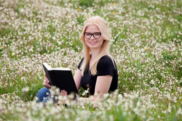 Mladá žena s knihou v louce — Stock fotografie