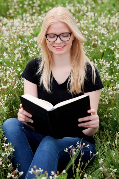 Mujer joven leyendo un libro en el prado — Foto de Stock