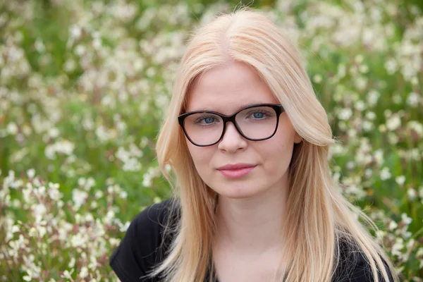 Gelukkig blond meisje omringd door bloemen — Stockfoto