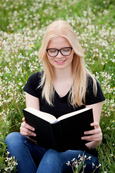 Mujer joven leyendo un libro en el prado — Foto de Stock