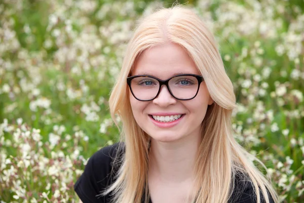 Felice ragazza bionda circondata da fiori — Foto Stock