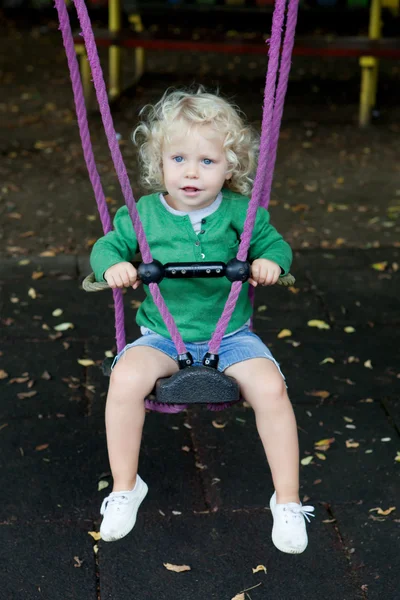 Funny blond boy riding on a swing — Stock Photo, Image