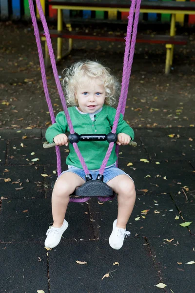 Funny blond boy riding on a swing — Stock Photo, Image