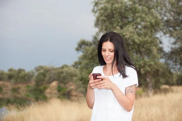 Entspannte brünette Frau schaut auf sein Handy — Stockfoto