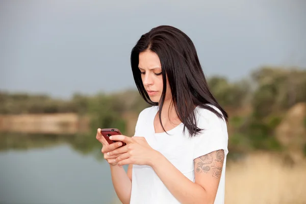 Entspannte brünette Frau schaut auf sein Handy — Stockfoto
