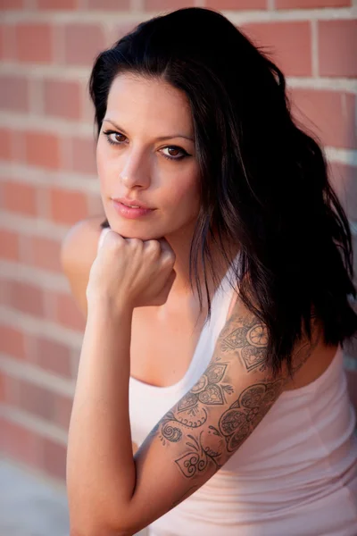 Beautiful brunette with red brick wall — Stock Photo, Image