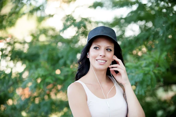 Brunette woman with headphones listening music walking in the fo — Stock Photo, Image