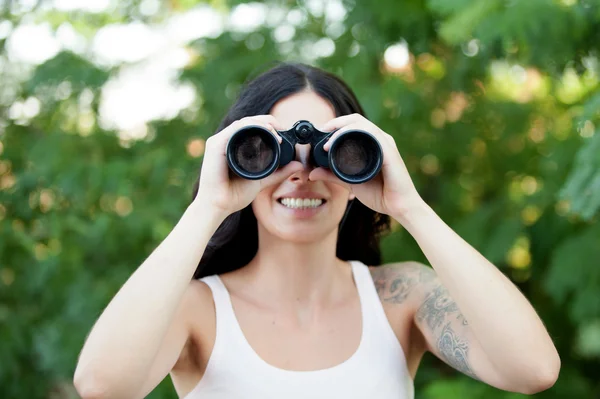Bruneta žena dívá dalekohledem a neúnavných th — Stock fotografie