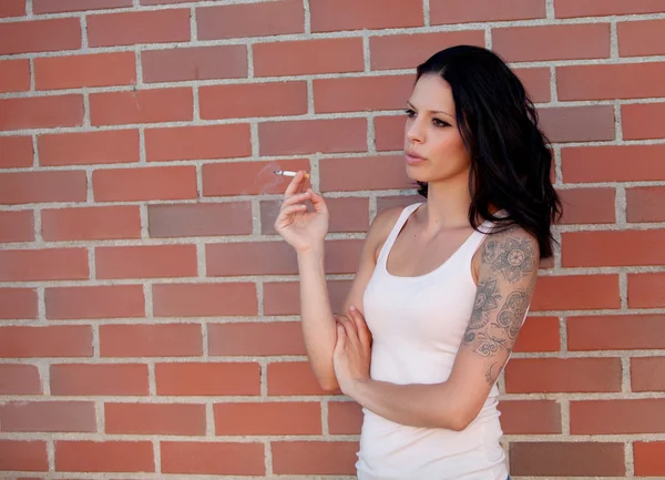 Brünette Frau mit engem Hemd, die eine Zigarette raucht — Stockfoto