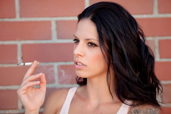 Mujer morena rebelde con camisa apretada fumando un cigarrillo — Foto de Stock