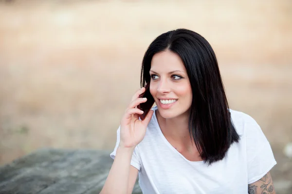 Entspannte brünette Frau im Park spricht auf dem Handy — Stockfoto