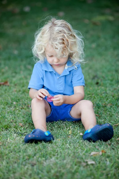 Menino bonito três anos sentado na grama — Fotografia de Stock