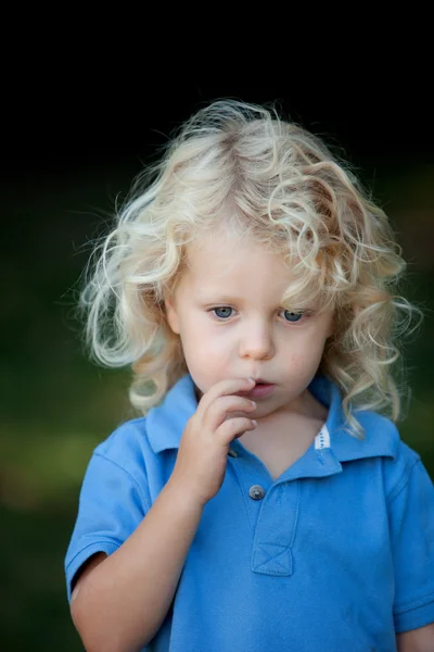 Zamyślony chłopiec trzy latka z długimi blond włosami — Zdjęcie stockowe