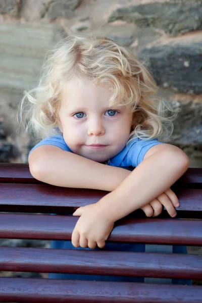 Klein kind verborgen achter een houten bankje — Stockfoto