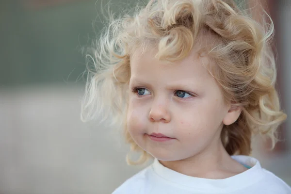 Schöner dreijähriger Junge mit langen blonden Haaren lizenzfreie Stockfotos