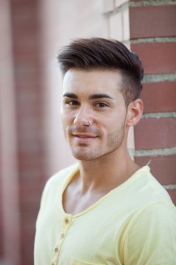 Yakışıklı adam bir tuğla duvara yaslanmış