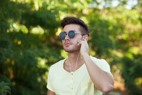 Killen i parken med solglasögon musik — Stockfoto