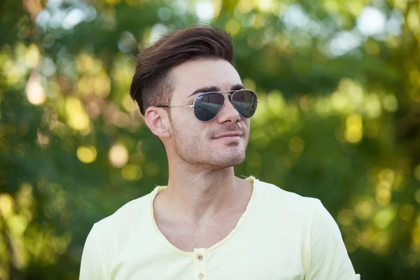 Attraktiv kille i parken med solglasögon — Stockfoto